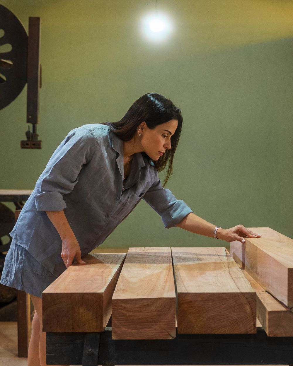 Designer Shine Braga examining sawn Mogno Bahia® pieces on a woodworking bench
